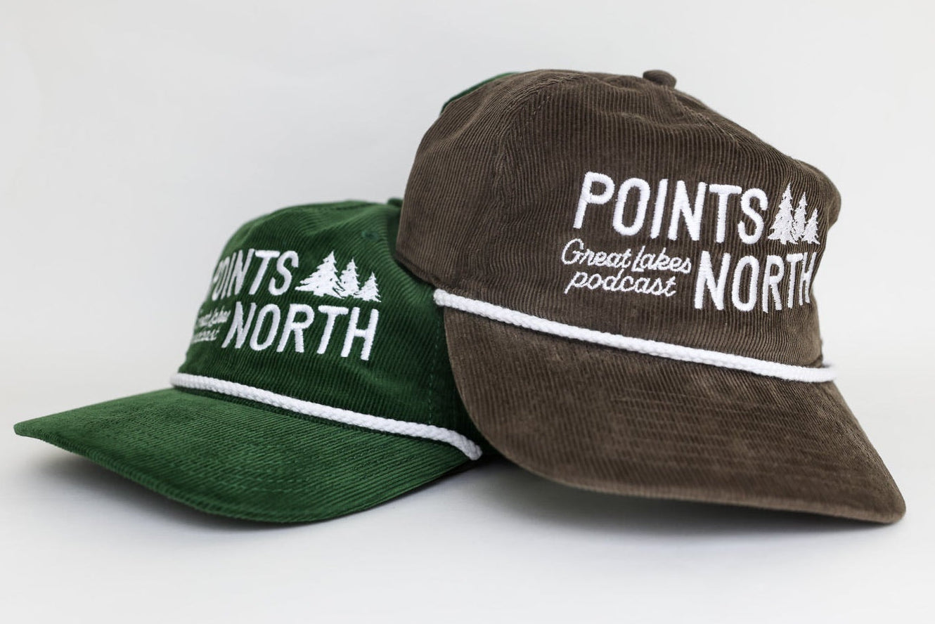 Two caps, one green and one brown, with 'Points North' branding on a white background.