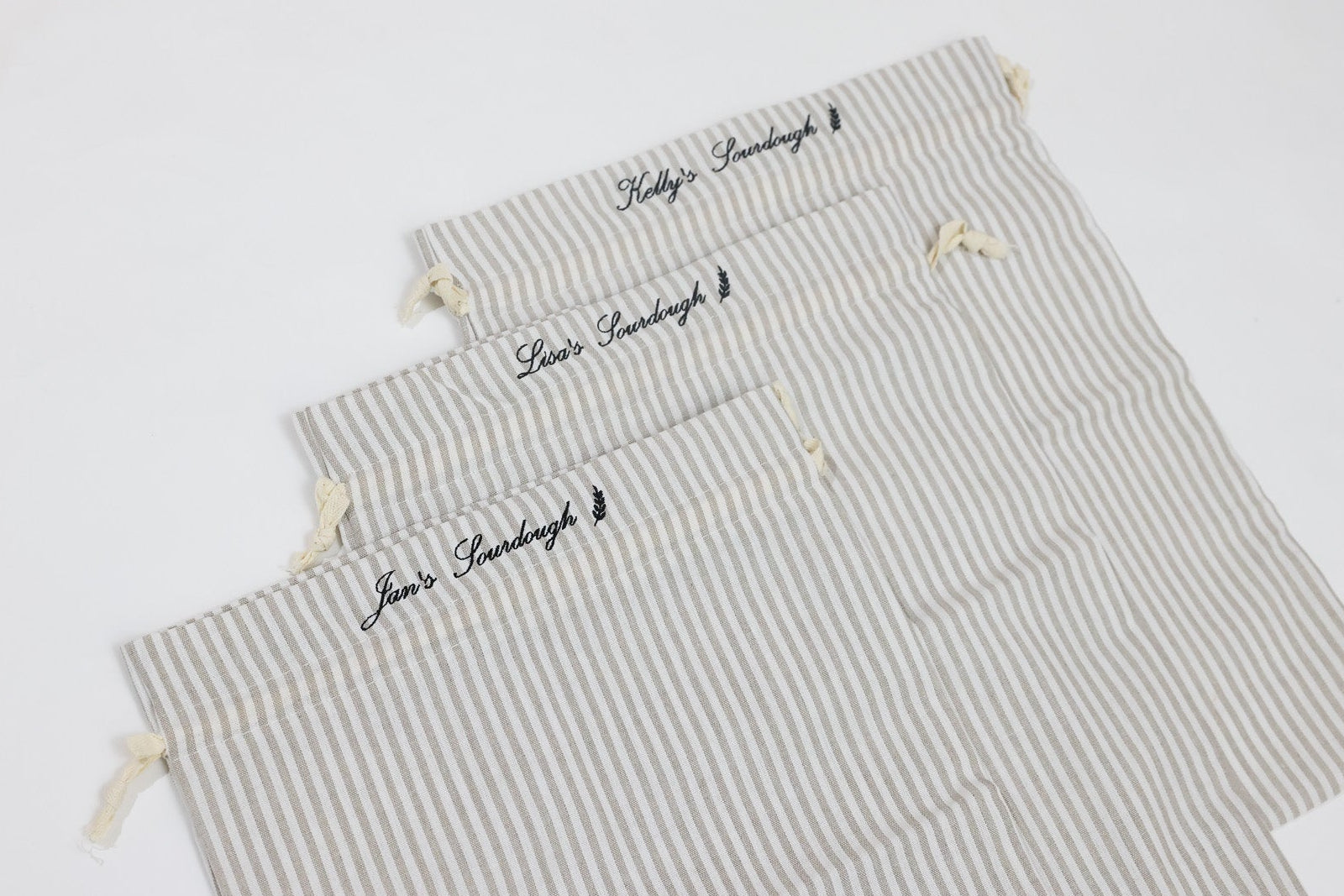 Set of three striped bags with embroidered text on a white background. custom embroidered sourdough bag.