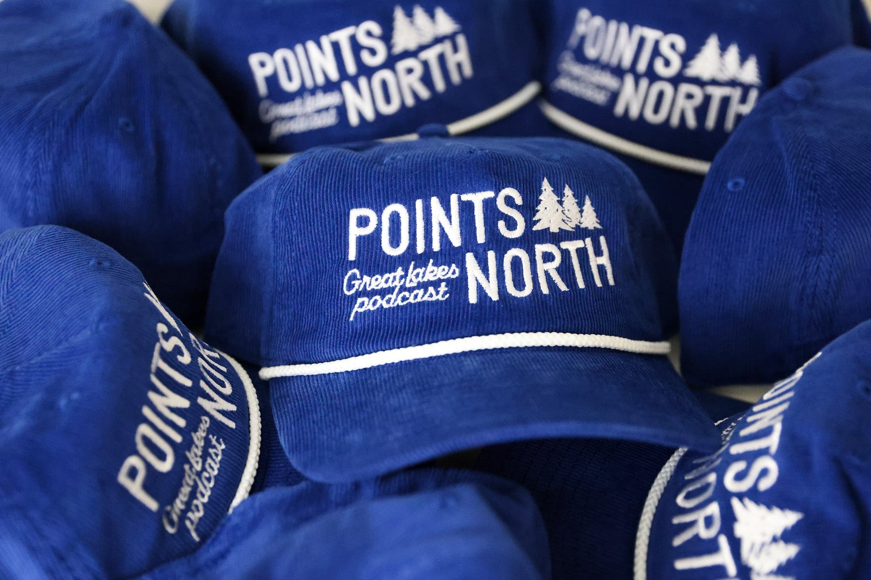 Blue caps with 'Points North' branding in a pile embroidered