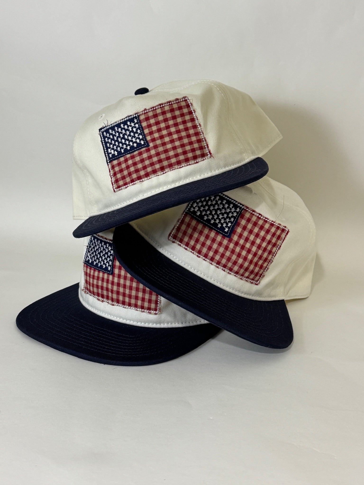 Three caps with American flag patches on a white background