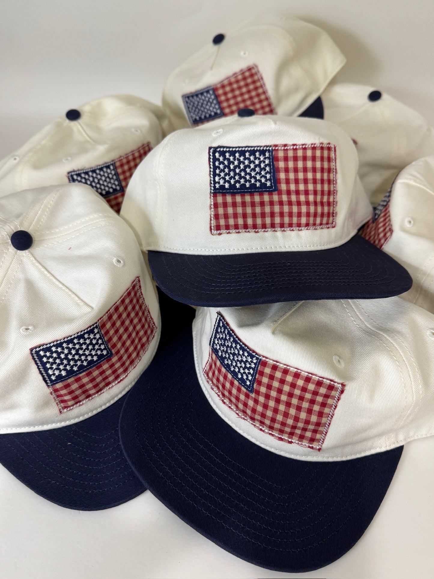 Four white and navy baseball caps with American flag patches on a white background