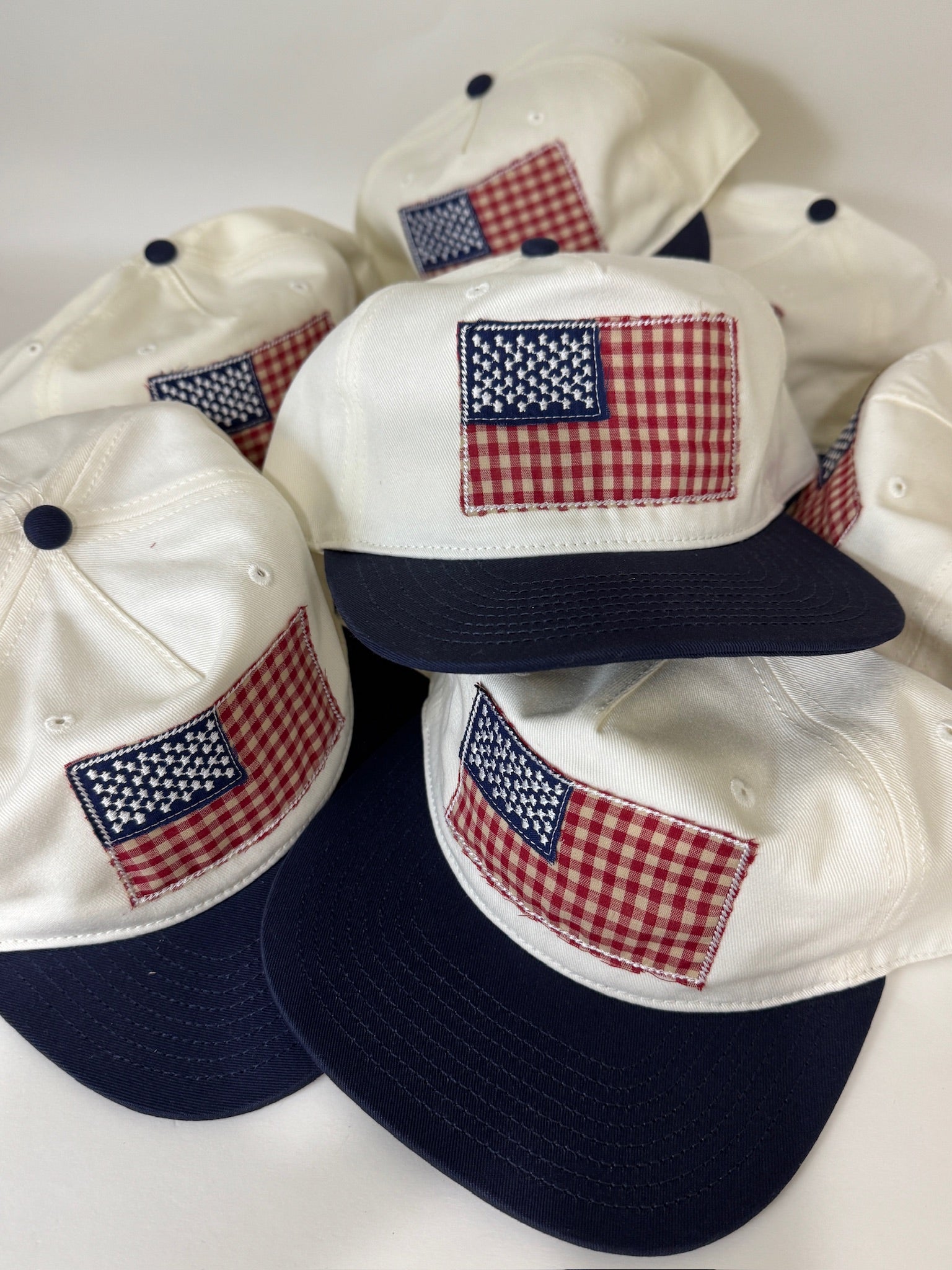 Four white and navy baseball caps with American flag patches on a white background
